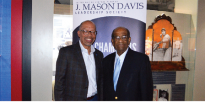 two men smiling in front of J. Mason Davis banner