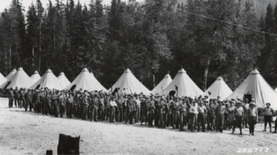 Group of men walking past tents in black and white image