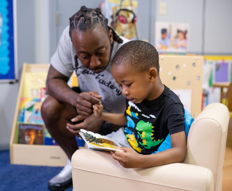 Father supports his son during a reading activity in an early learning classroom.