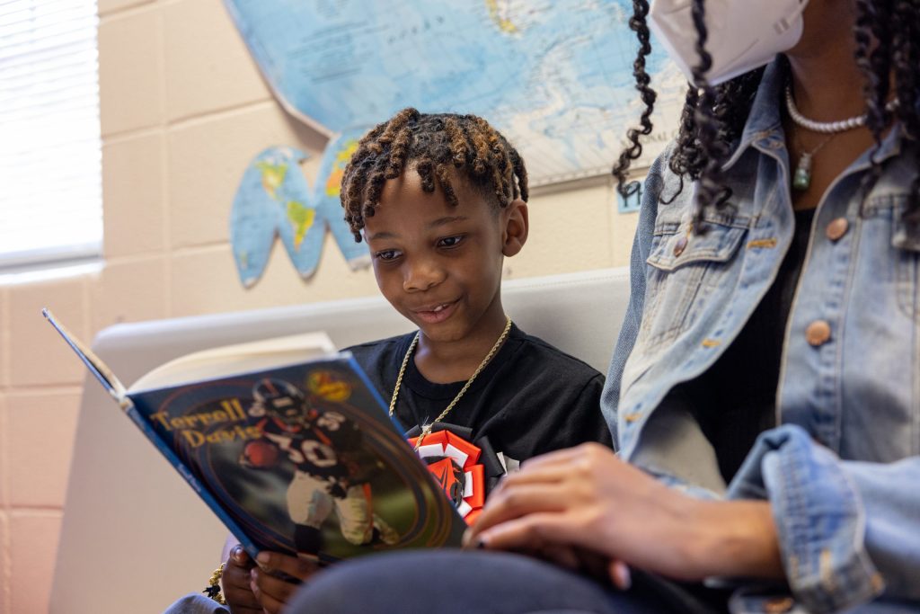 a young boy in a black t-shirt reads a book