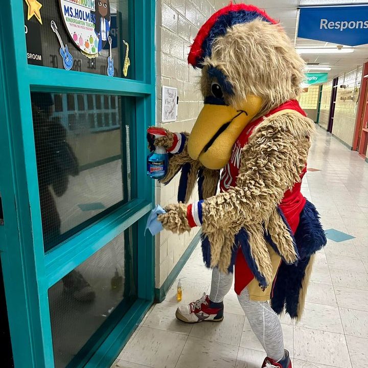 Commander, a pelican and Birmingham Squadron's mascot, joins in on beautification efforts by cleaning windows in Fairfield Primary School.