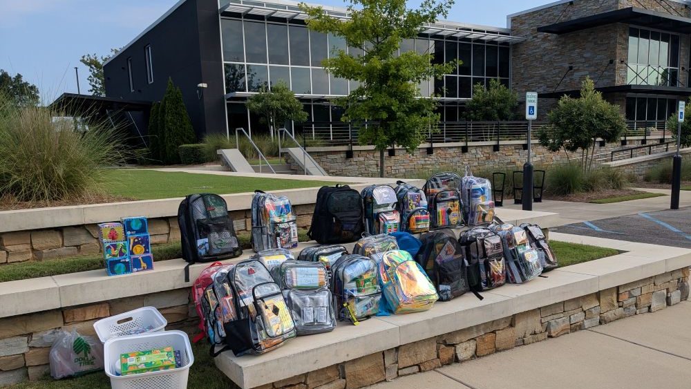 Clear backpacks filled with school supplies are displayed outside a building as part of the BUSA Back-to-School Day of Action.