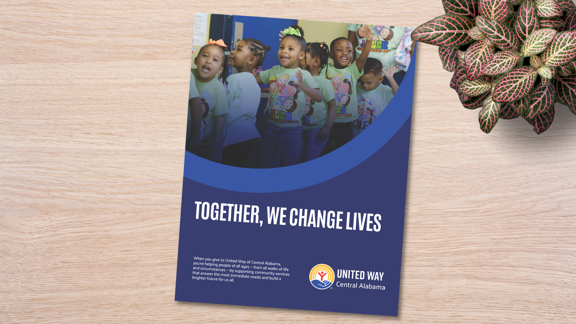 Cover of the United Way of Central Alabama “Together, We Change Lives” brochure for the 2026 campaign toolkit, shown on a wood desk with children featured on the cover.