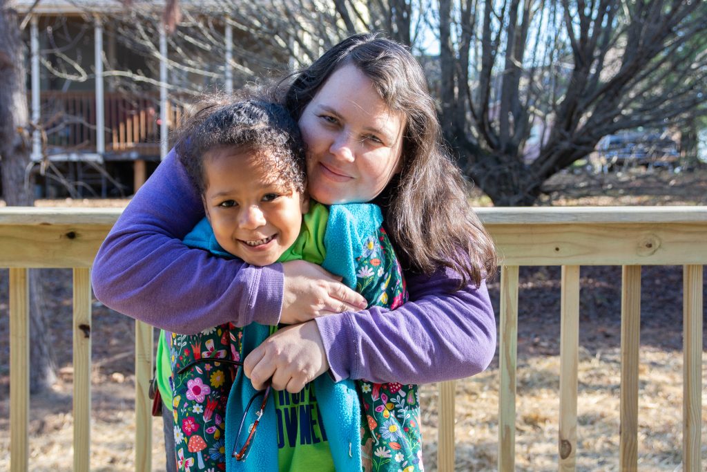Liz Doss holds her daughter Madeline as they pose for a picture on the deck of their new home, which was built by Habitat for Humanity.