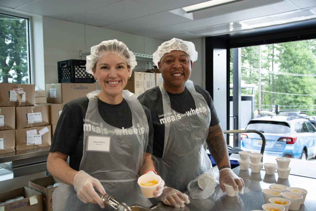 Two meals on wheels volunteers work side by side in the kitchen