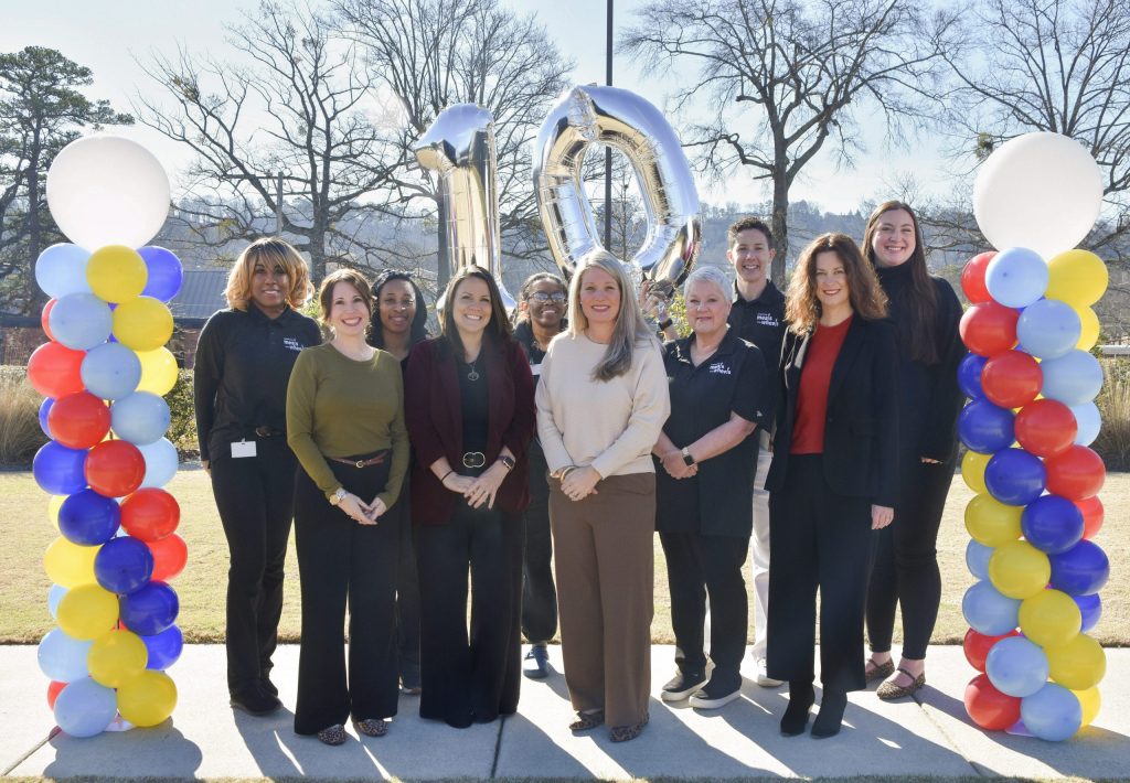 Meals on Wheels staff celebrate the program’s 10th anniversary with balloons and a large silver “10.”