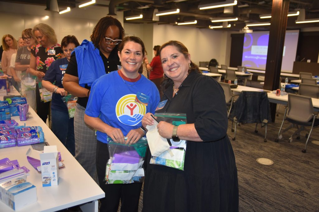 Two volunteers hold kits of period supplies assembled for distribution across Central Alabama.