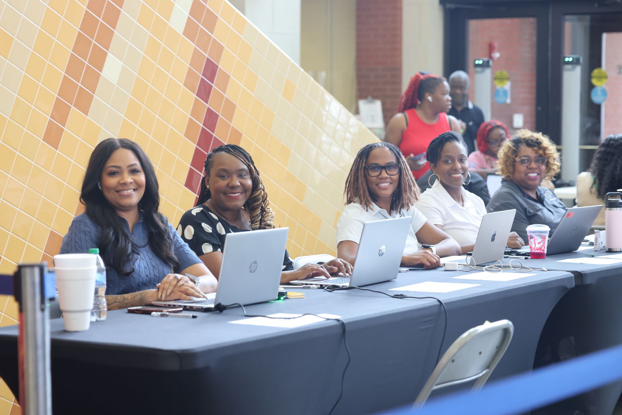 United Way staff and volunteers sit at a registration table with laptops, assisting community members seeking food and emergency resources during a crisis response effort.