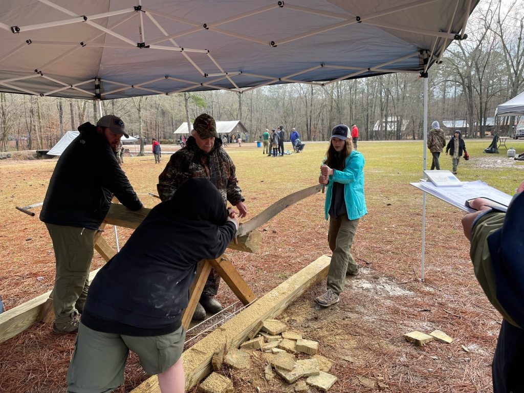 Isabelle Dionne and other Scouts use a two-person crosscut saw during an outdoor skills activity.