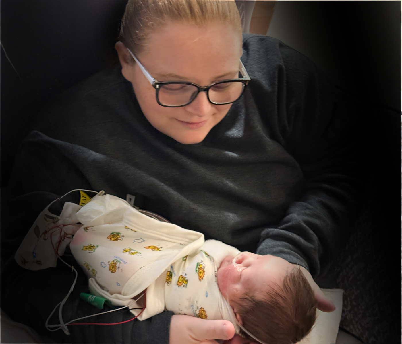 Mother holding her premature newborn during a hospital stay, representing families supported during times of crisis.